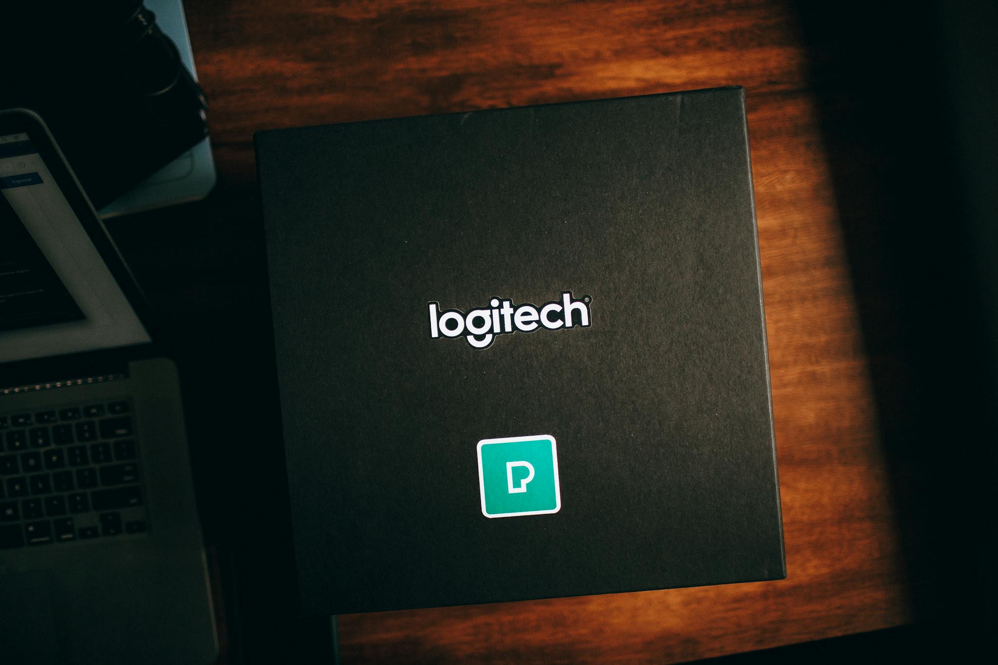 Top view of a Logitech branded box with design elements on a wooden surface, perfect for showcasing product packaging.
